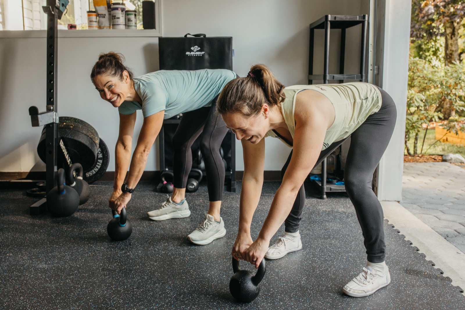 Two women performing kettlebell deadlifts during a small-group strength session